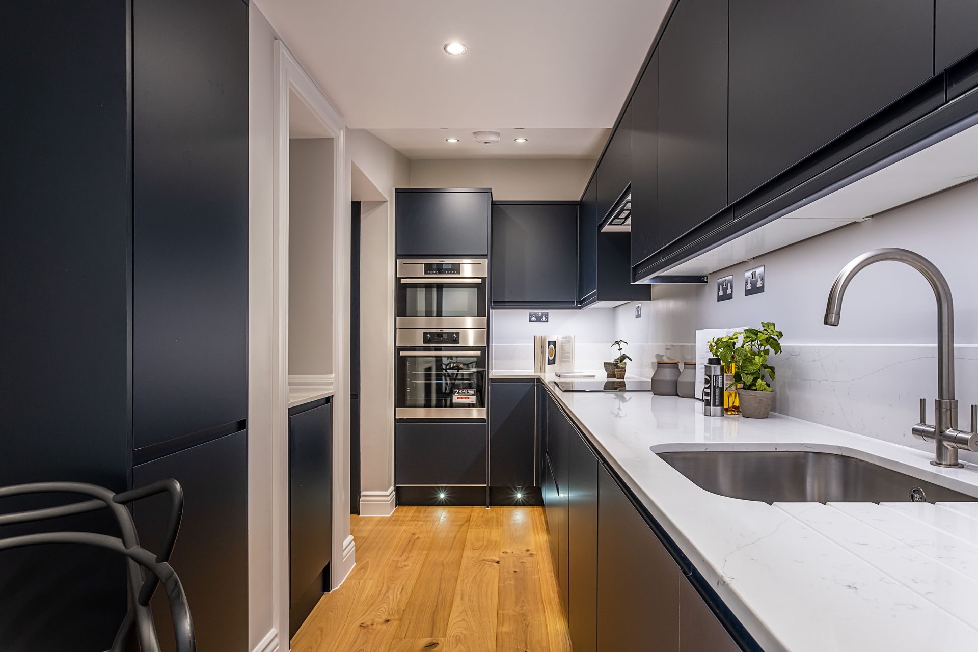 A kitchen with black cabinets and a stainless steel sink.