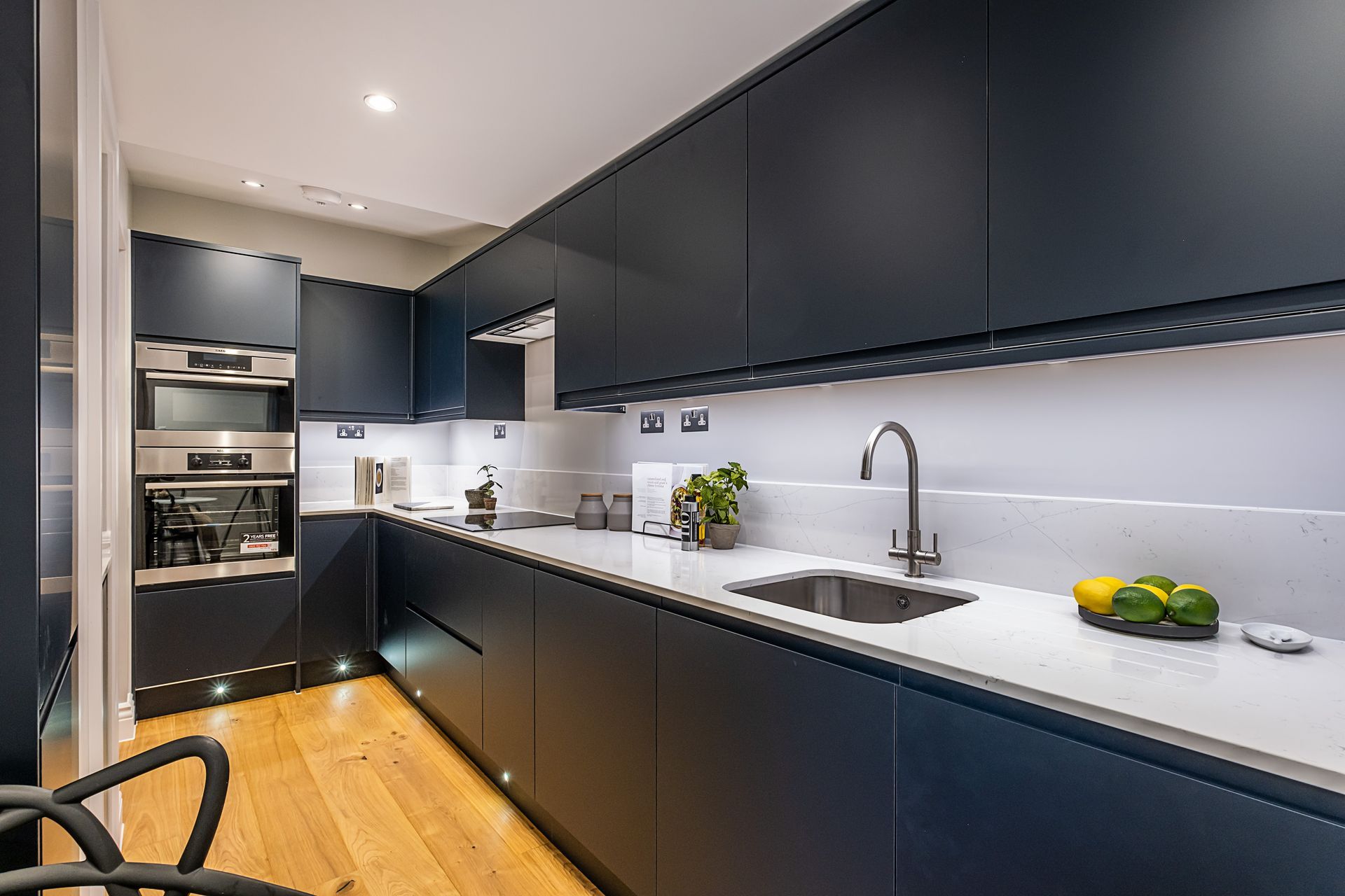 A kitchen with blue cabinets , a sink , and a stainless steel oven.
