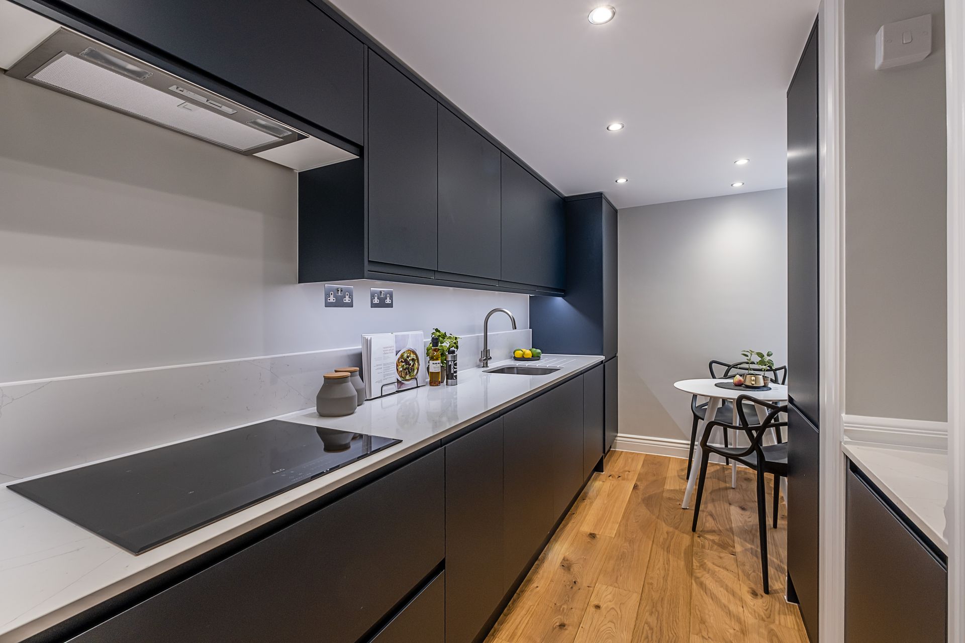 A kitchen with black cabinets and white counter tops and a stove top oven.