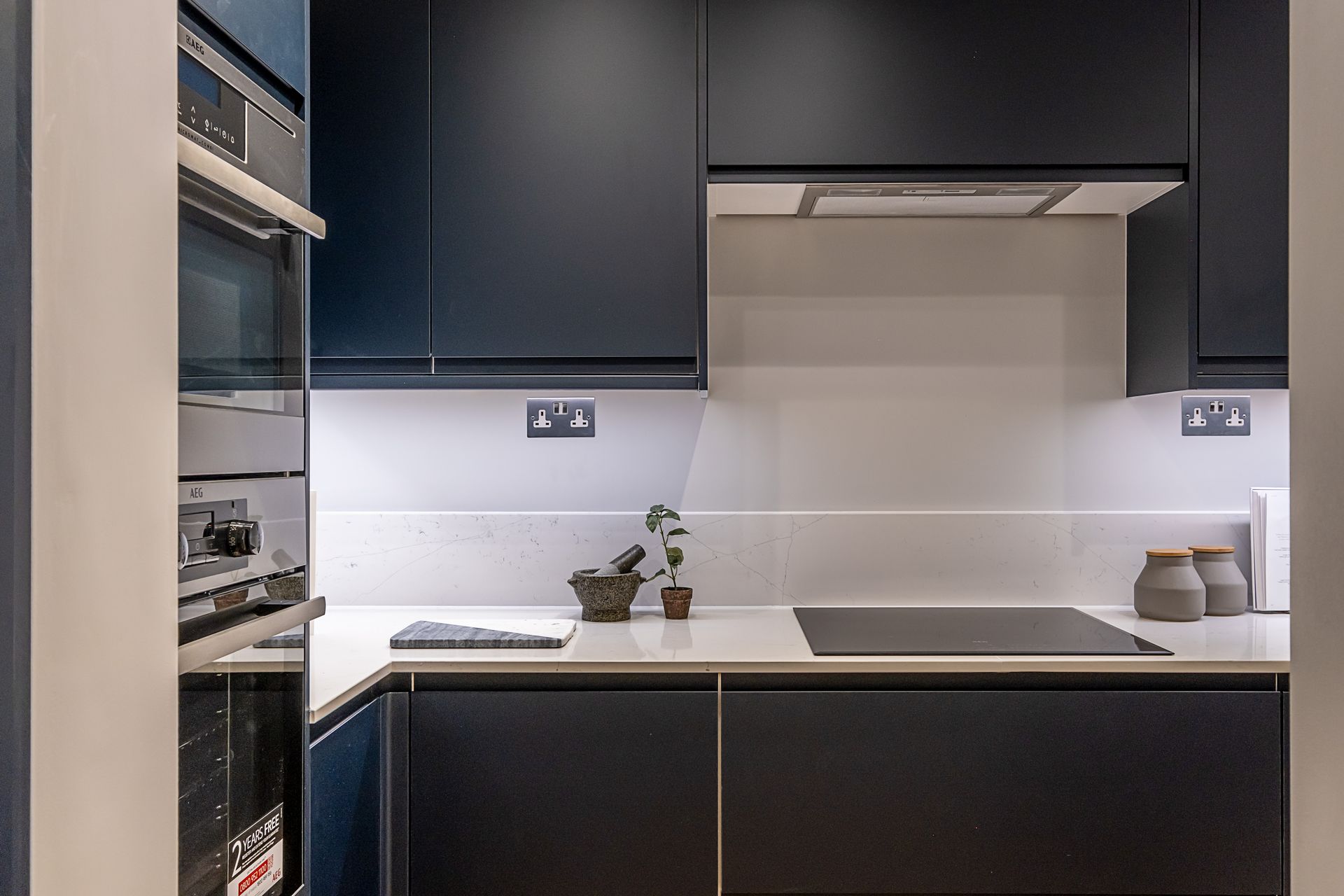 A kitchen with black cabinets , a stove top oven , and a microwave.