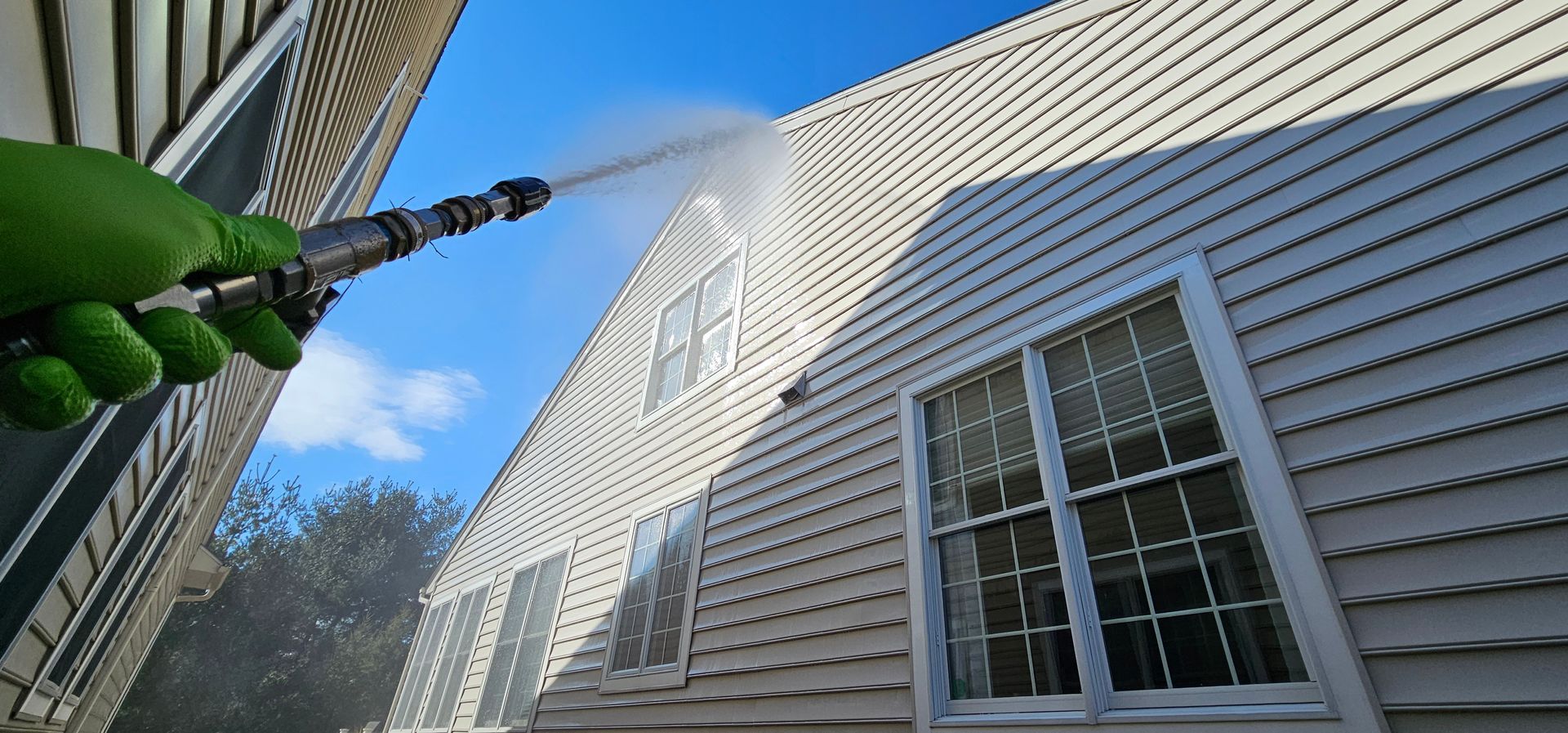 A person wearing a mask and cap uses a laptop in a woodworking shop, tools nearby.