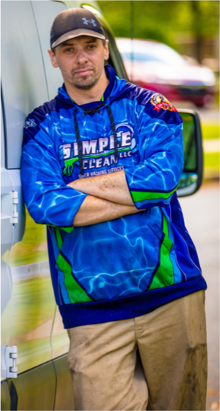 Man in blue hoodie leans against a white van, arms crossed.