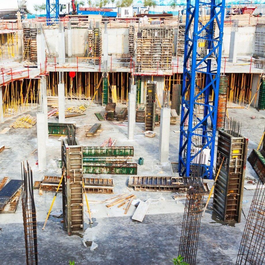 Construction site with concrete forms, rebar, and a blue crane.