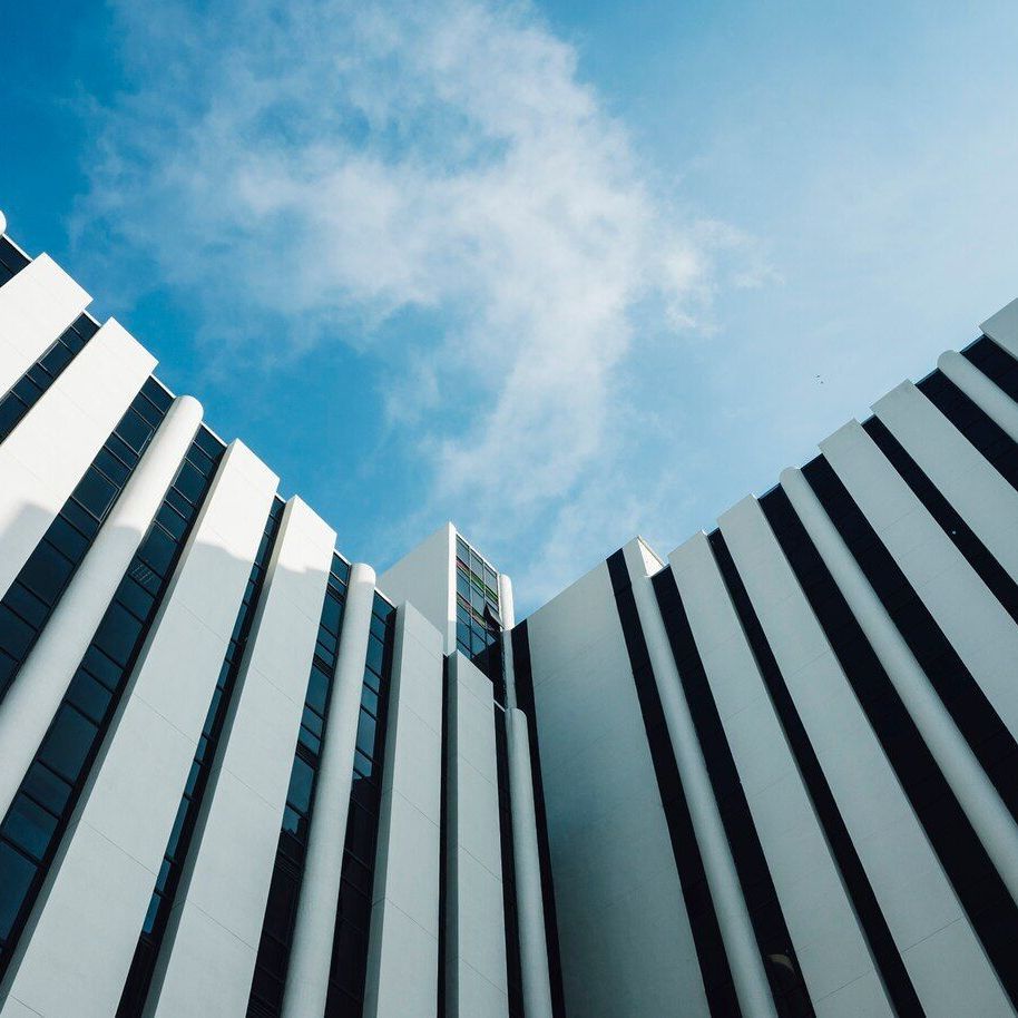 White and black striped modern building against a blue sky with fluffy white clouds.