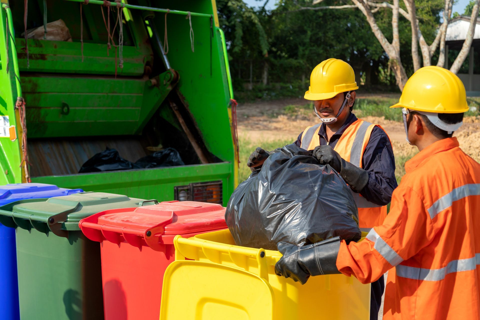 Two men are loading garbage into a garbage truck.