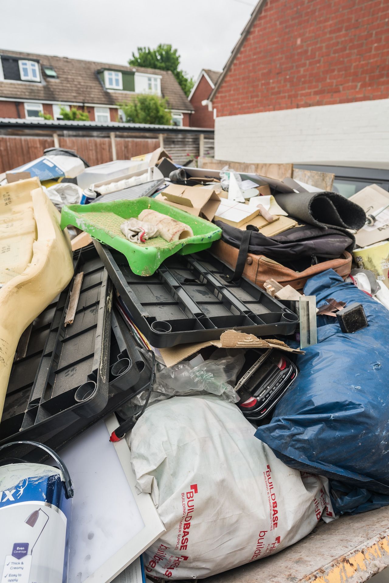 A pile of trash is sitting on top of a dumpster.