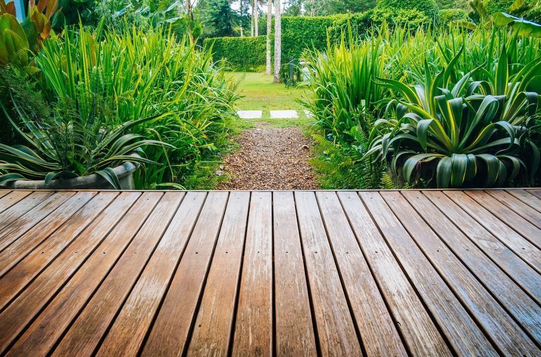 There is a wooden deck in the middle of a garden.