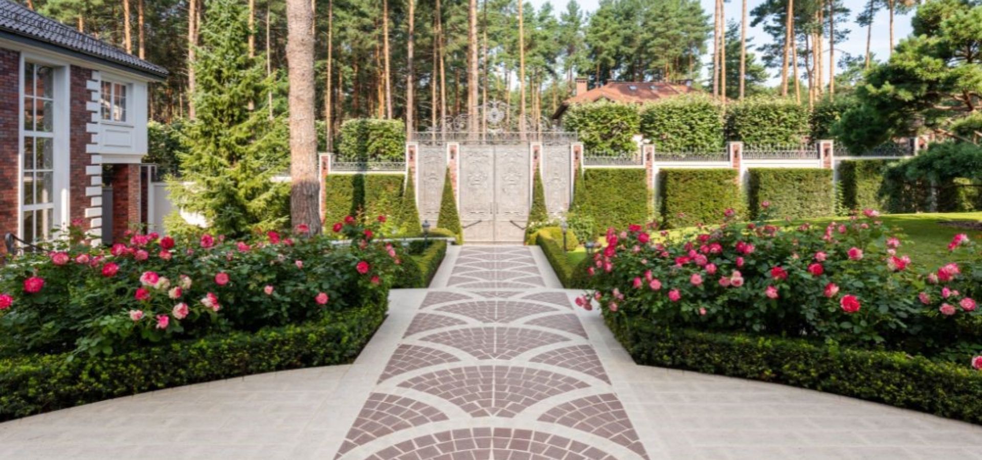 A brick walkway leading to a house surrounded by flowers and bushes.
