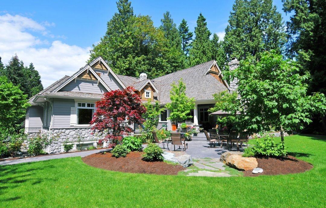 A large house with a large lawn in front of it surrounded by trees.