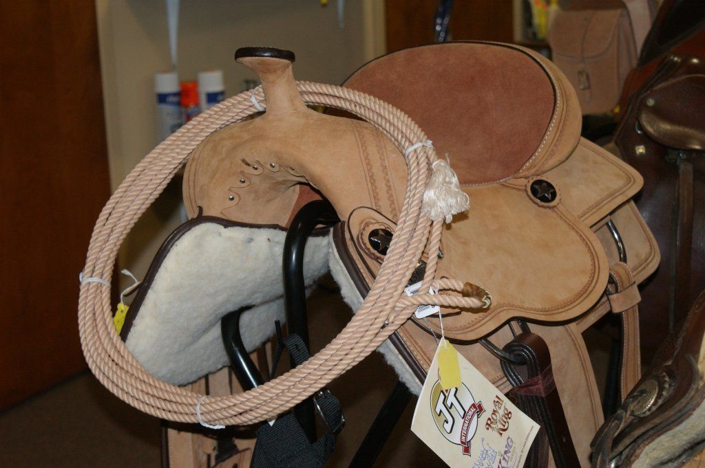 Tan leather Western saddle with coiled rope.