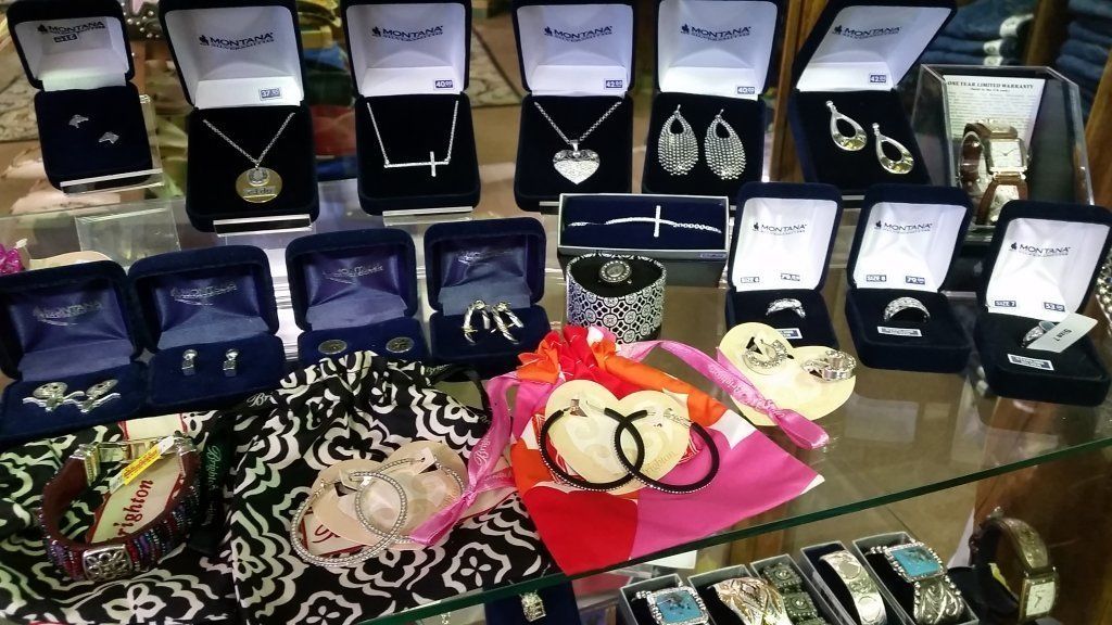 Jewelry display case with necklaces, earrings, rings, and watches in boxes and on a glass shelf.