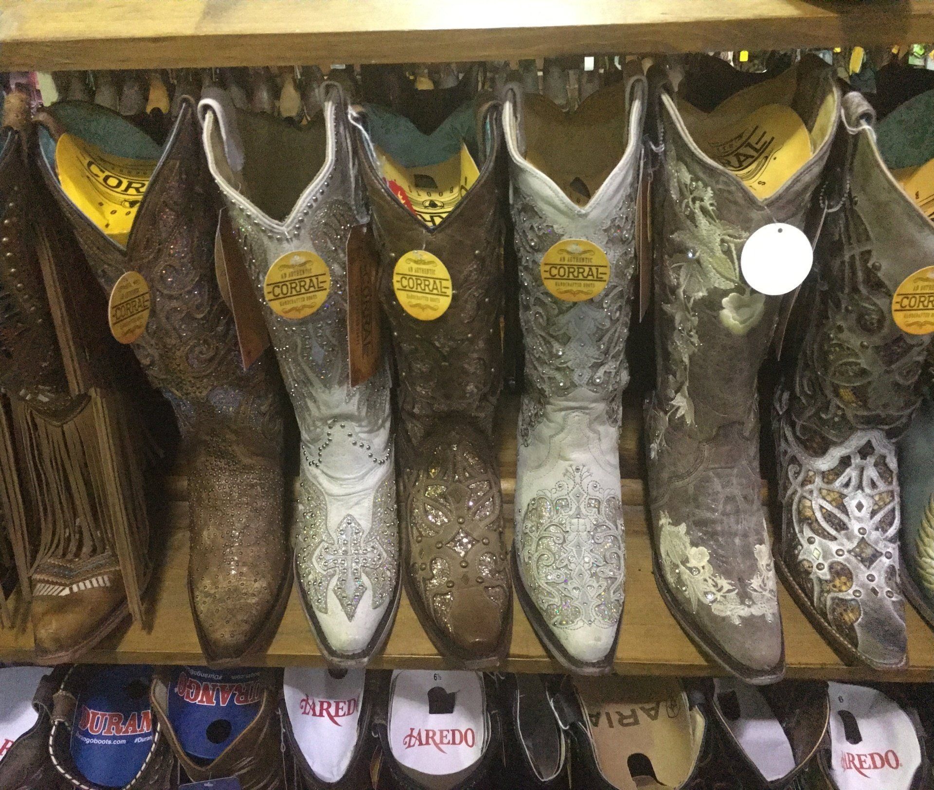 A row of colorful cowboy boots displayed neatly on shelves in a retail store.
