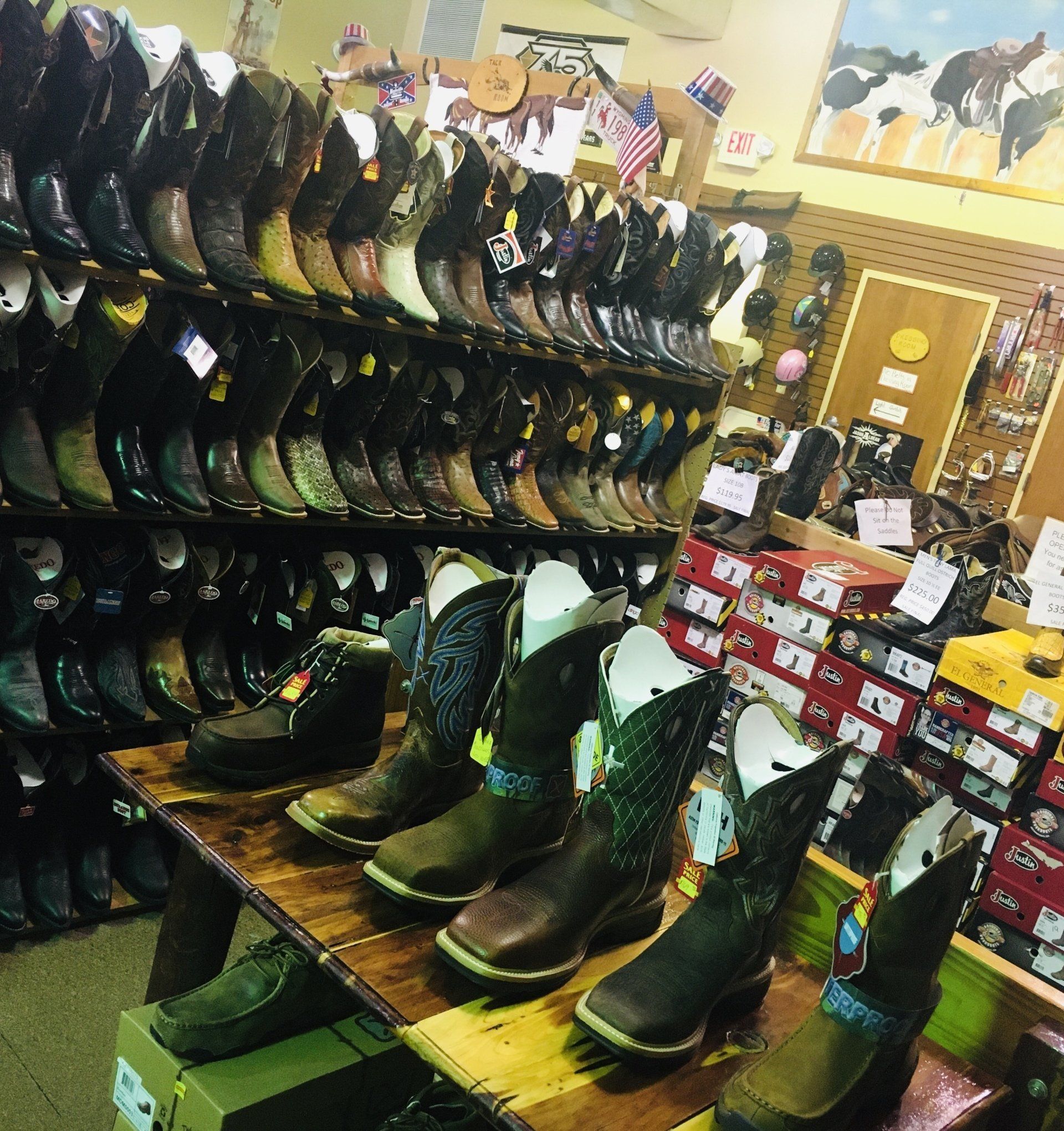 Rows of cowboy boots on shelves in a store. Some boots are displayed on a wooden table.