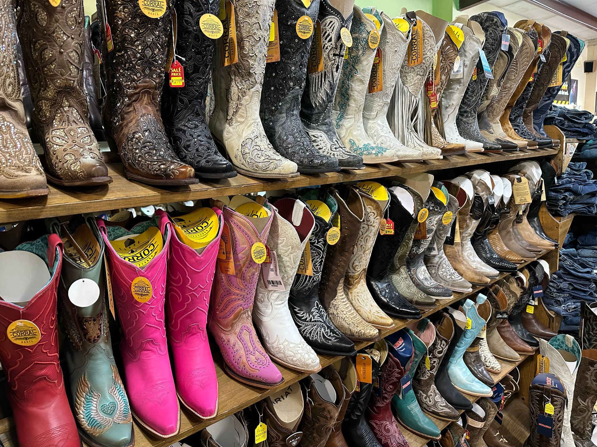 Two embellished cowboy boots, one floral, one skull-themed, displayed on a brown hide rug.