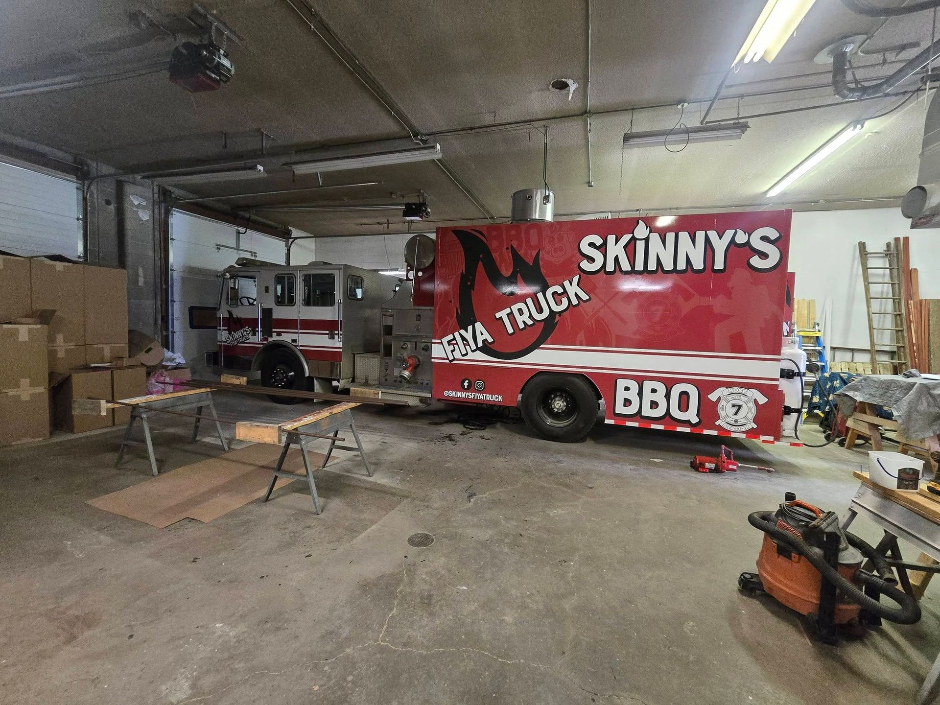 A person holding a baby up in the air indoors near a window, baby smiling.