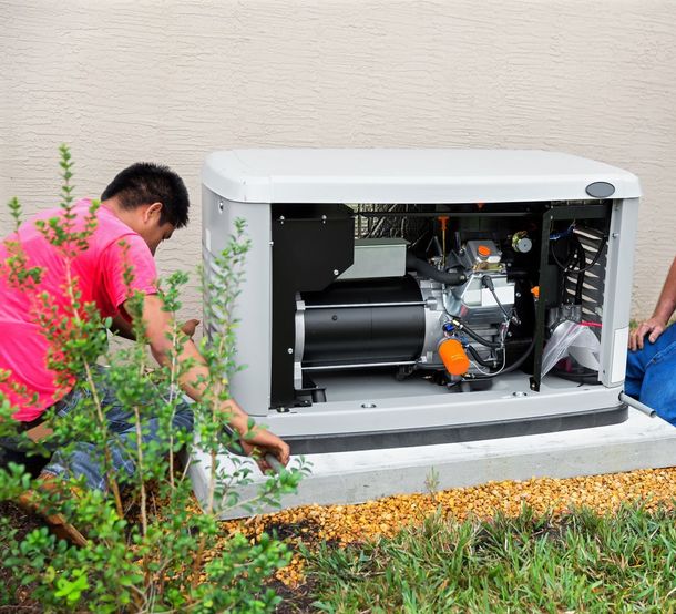A man is working on a generator outside of a house.