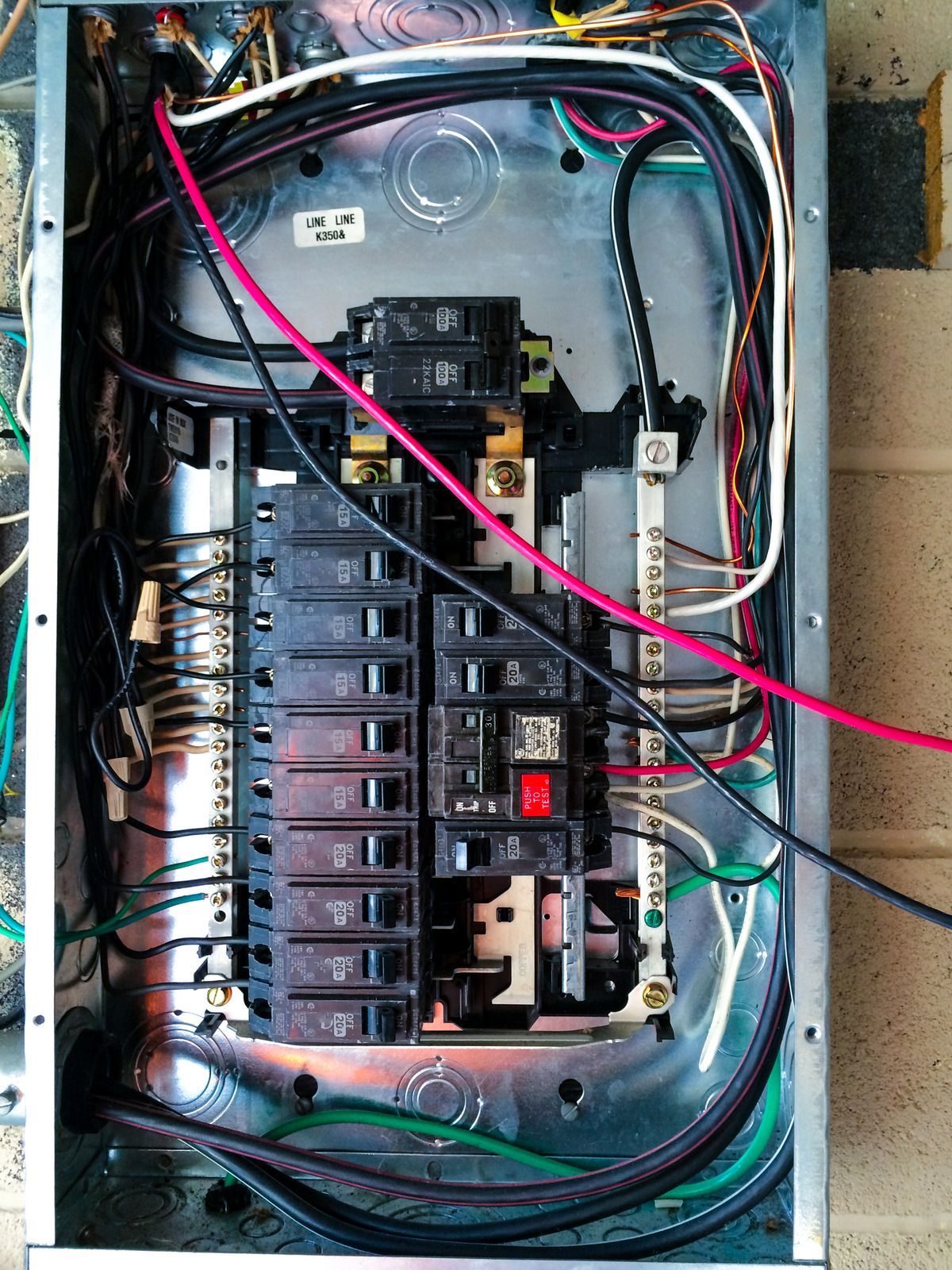 Open electrical panel with wires and circuit breakers.