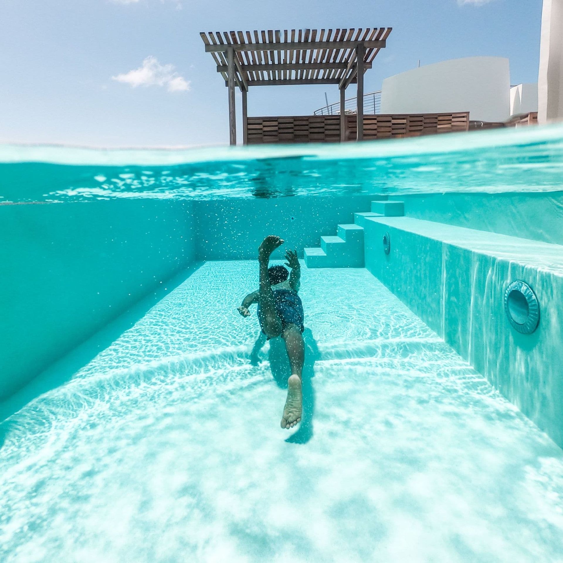 Person Swimming Underwater in a Turquoise Pool, With a Pergola Above — Creative Pools and Spas in Mornington, VIC