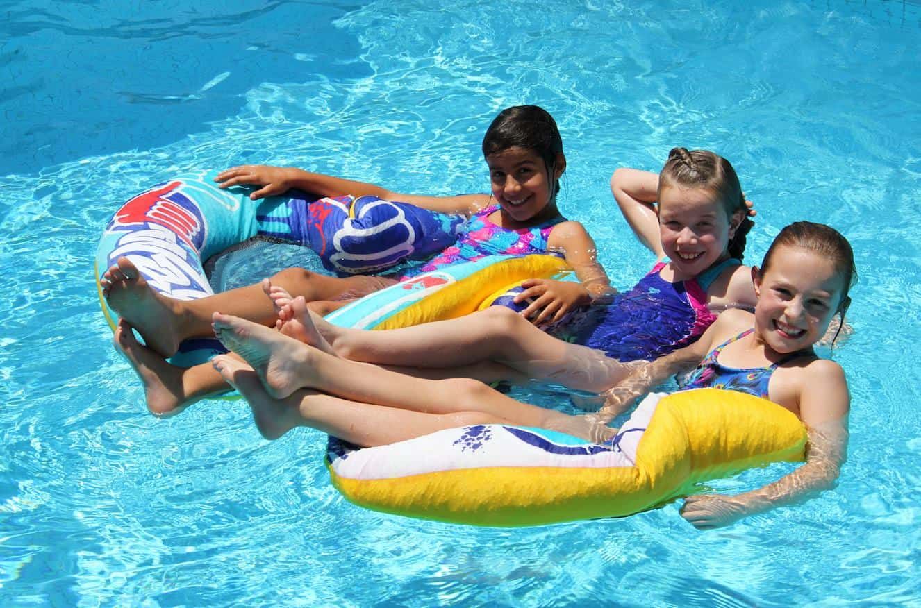 Three Kids in Swimsuits Relaxing on a Colorful Inflatable Raft — Creative Pools and Spas in Rosebud, VIC