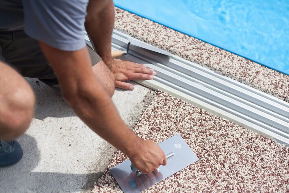 Person Using a Trowel to Smooth Textured Concrete Around a Pool's Edge — Creative Pools and Spas in Rosebud, VIC