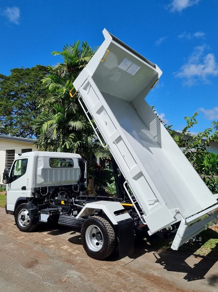 A white dump truck is parked on the side of the road.