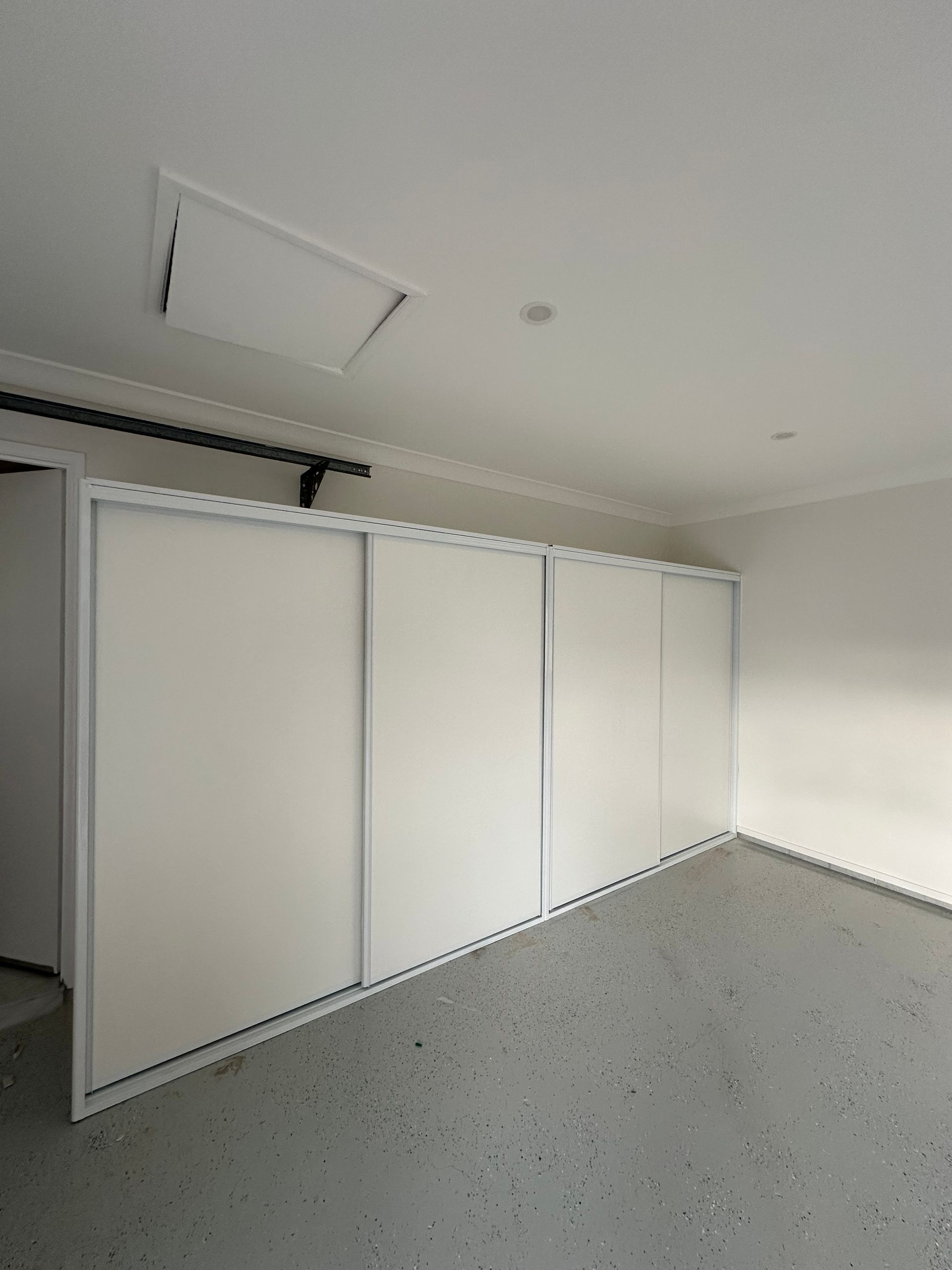A large empty room with white walls and a ceiling fan.