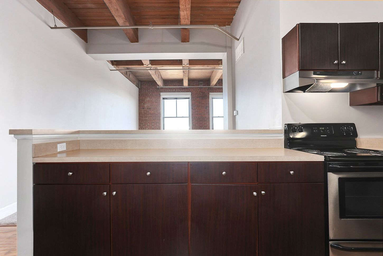 An empty kitchen with brown cabinets and a stove