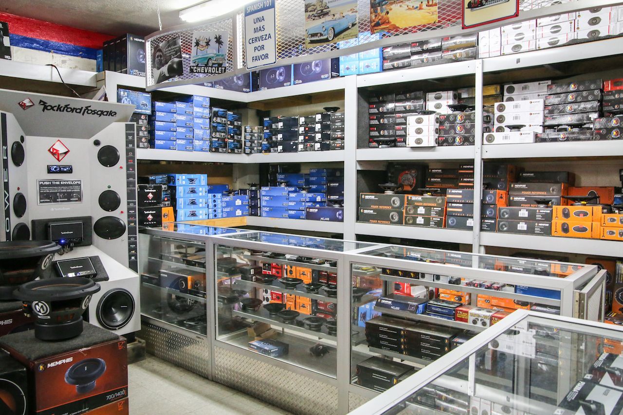 Inside a car audio shop. Shelves stocked with stereo equipment. Speakers on display.