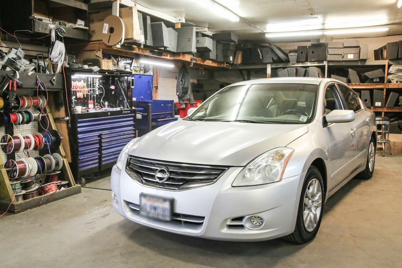 a silver nissan altima is parked in a garage .