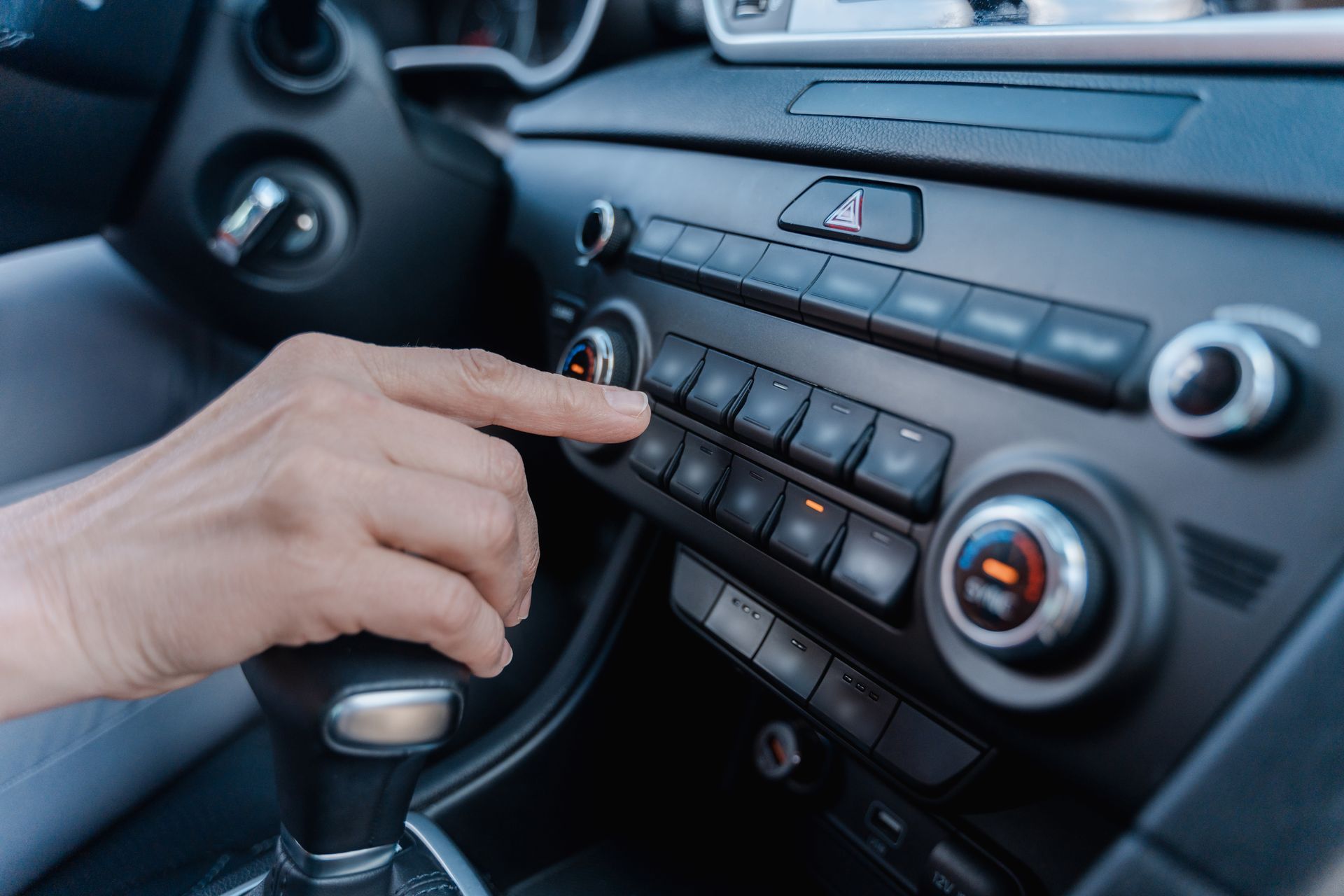 a person is adjusting the air conditioner in a car .