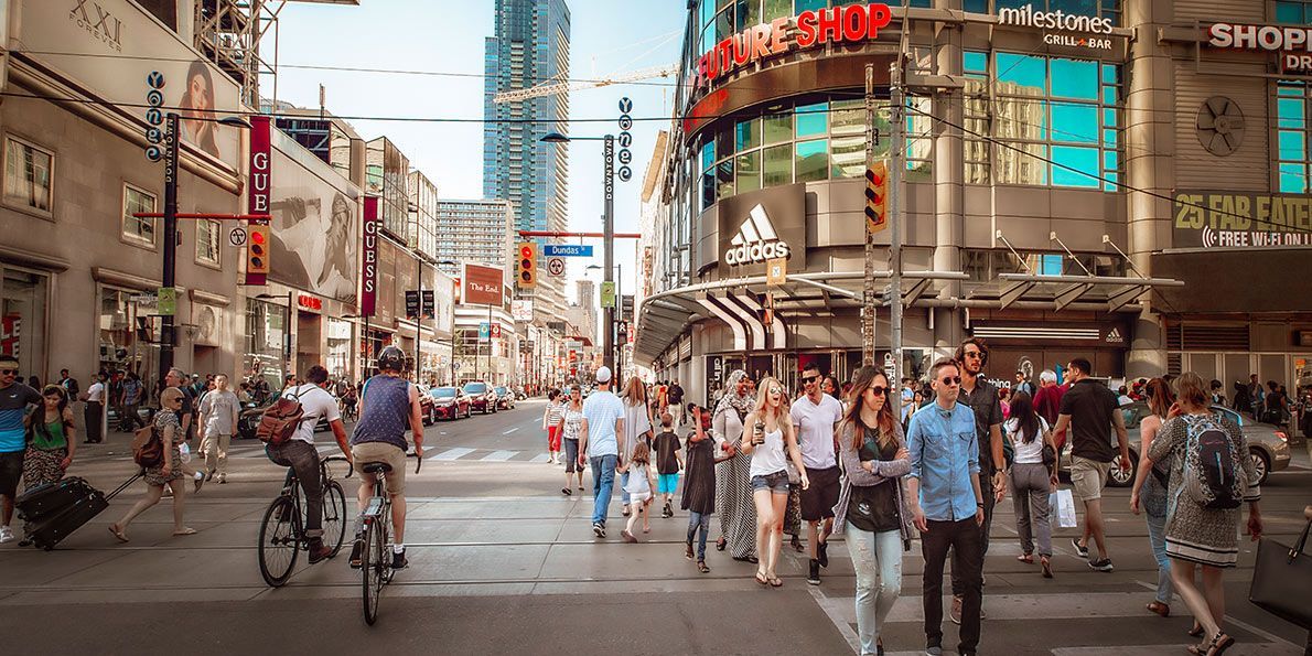 A group of people are walking down a street in front of a store called shoe shop