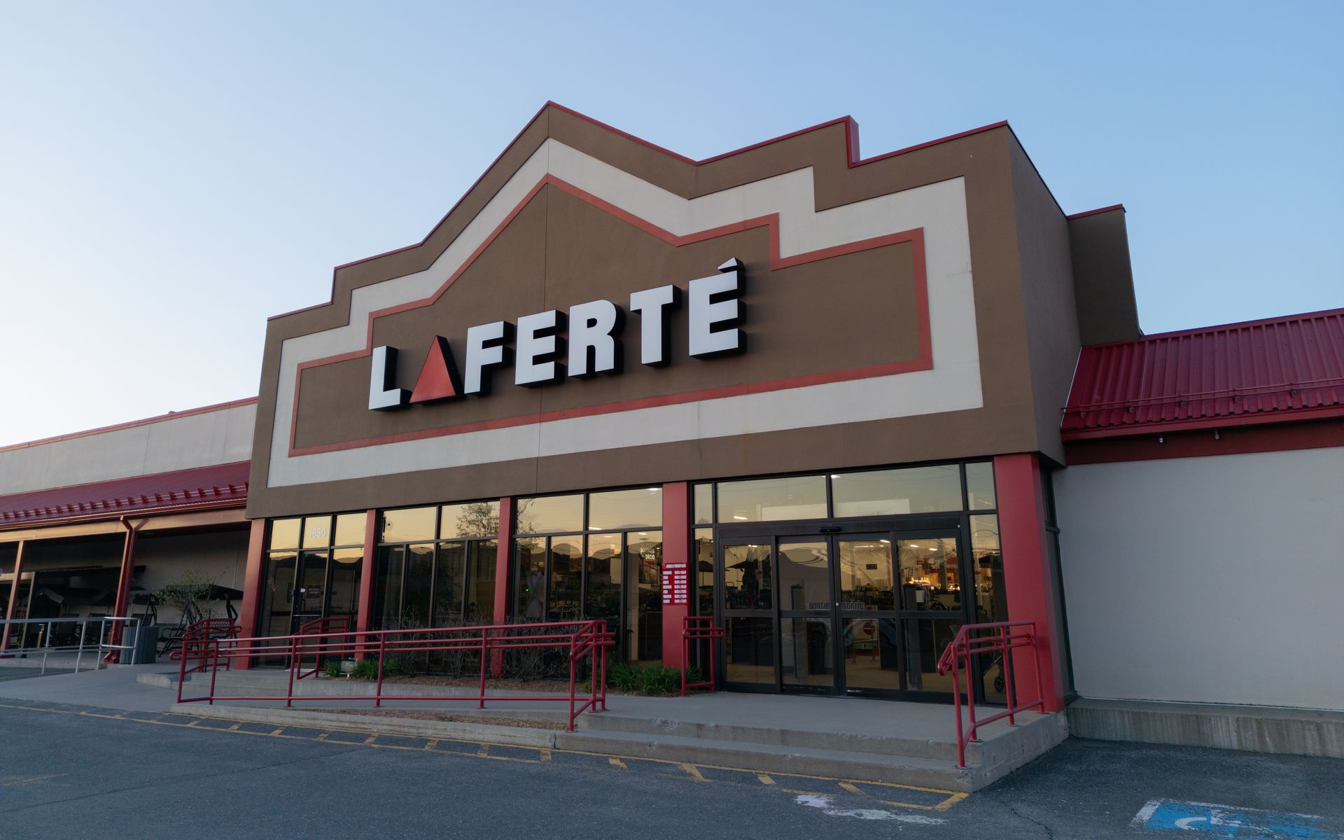 Extérieur du magasin LAFERTÉ : bâtiment marron avec garnitures rouges, vitrines et enseigne.