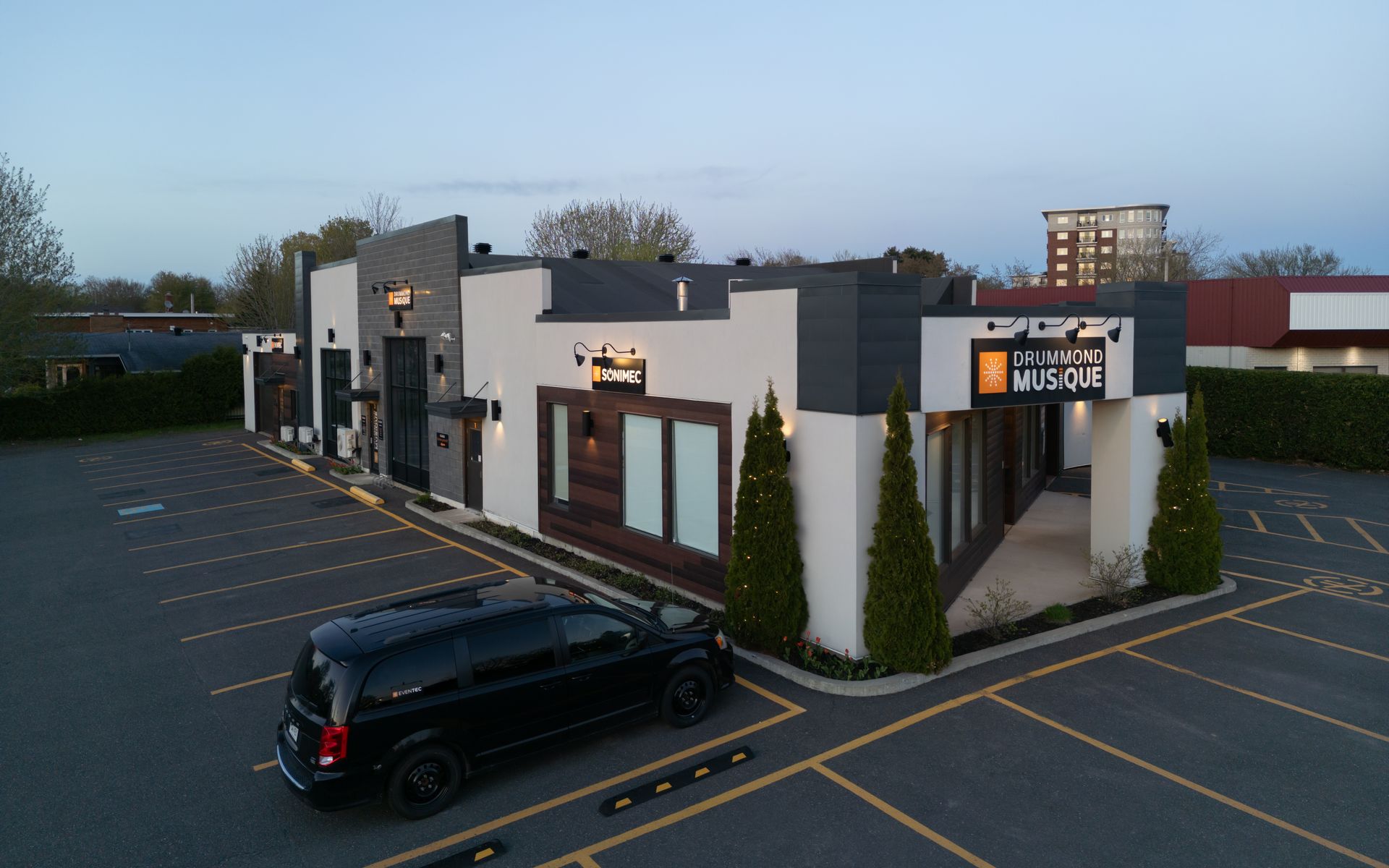 Vue extérieure d'un bâtiment moderne avec une camionnette noire garée devant. L'enseigne indique « Vibe Music ».