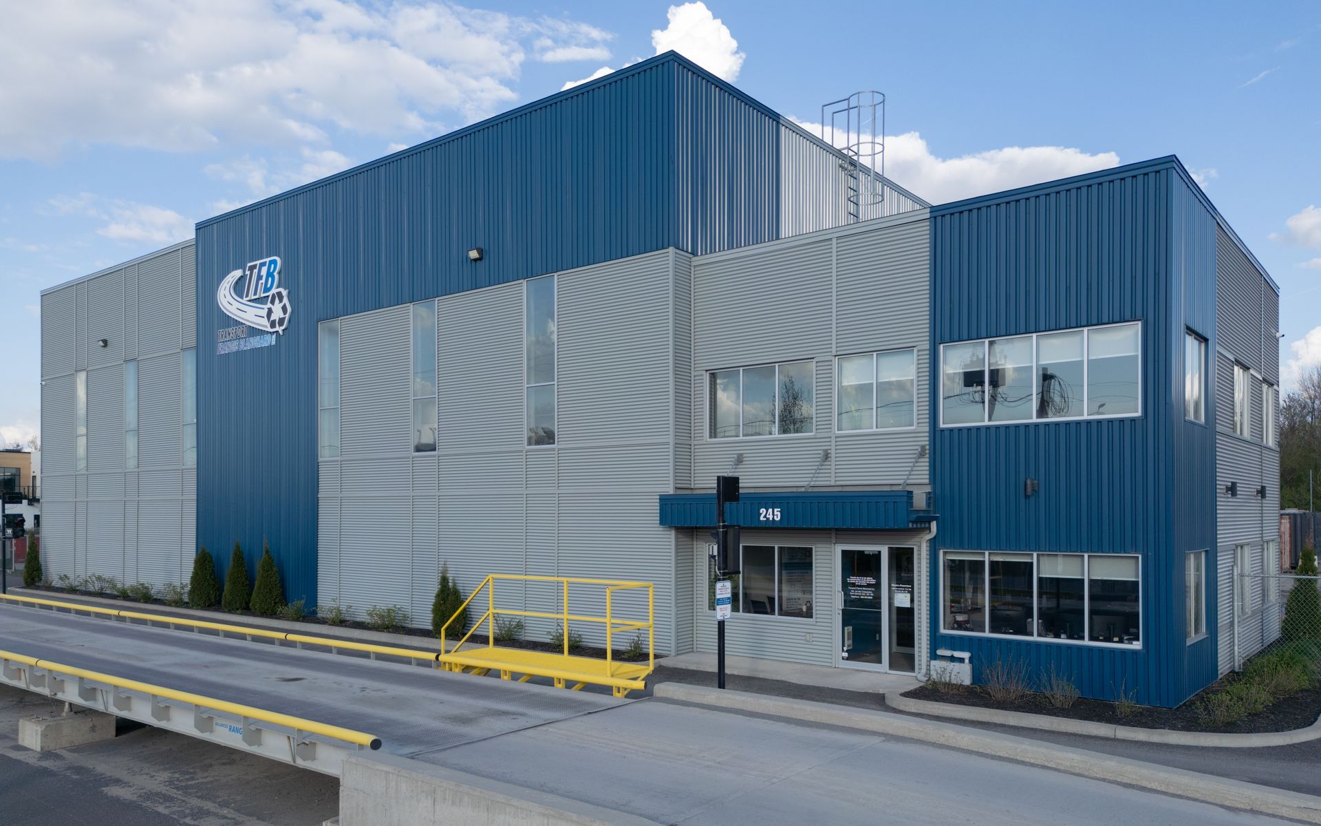 Bâtiment industriel bleu et gris avec rampe de chargement.