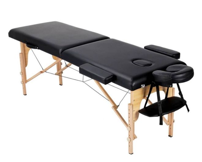 A black massage table with wooden legs on a white background | St. Louis, MO | Lashing Out Loud