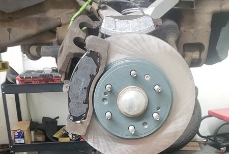 Car brake system with a rotor, caliper, and brake pads.
