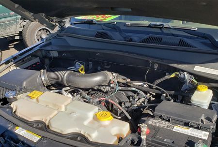 Open car engine bay with black components, various tanks, and air intake hose.