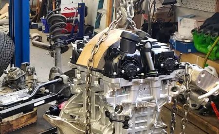 Yellow Hyundai forklift with driver, parked in front of a camper.