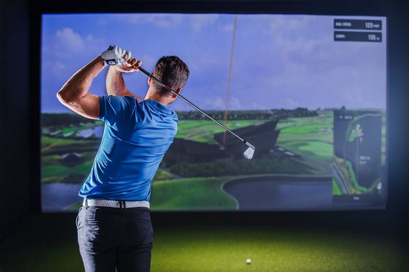 A person is playing a game of golf in a simulator.