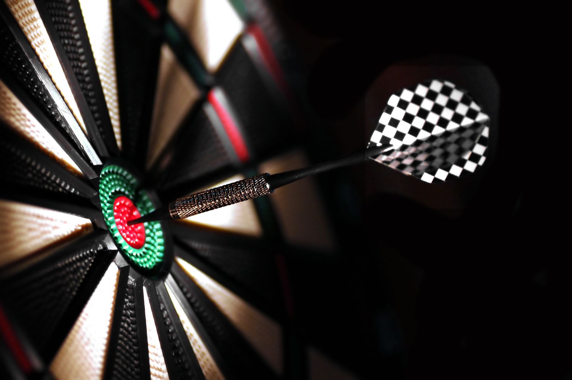 Dart in center of dartboard, with red bullseye and checkered flight.