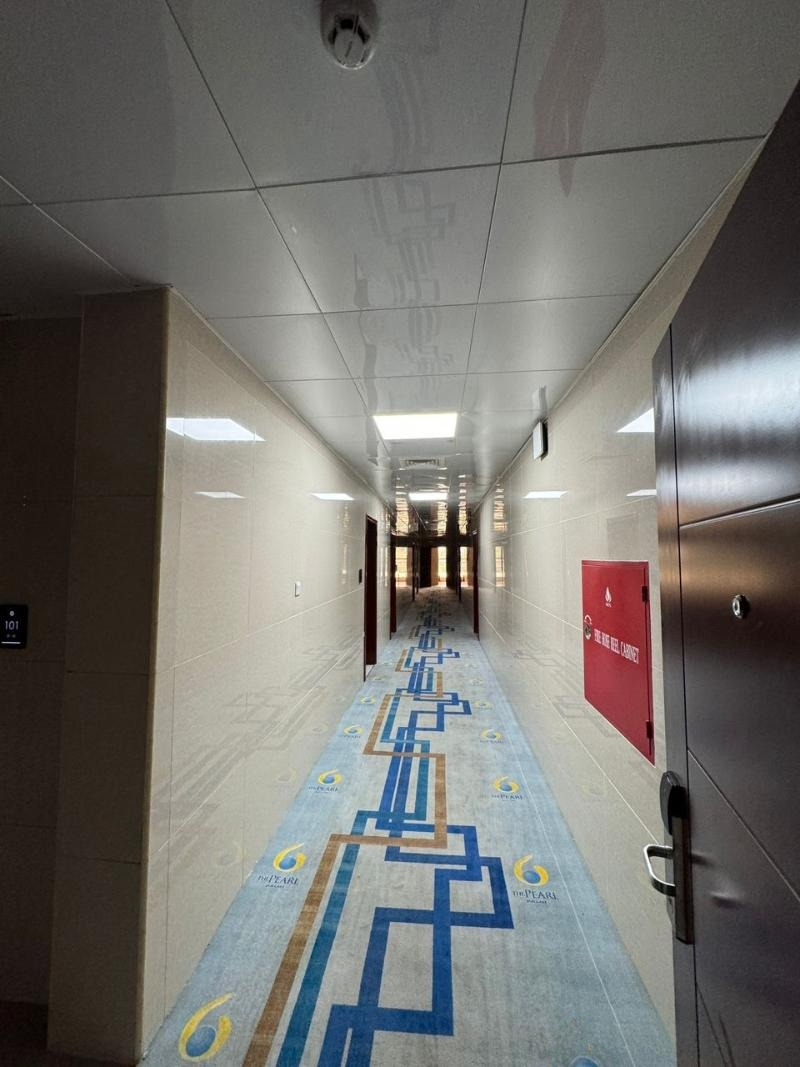 A long hallway with a carpet and a door in a building.