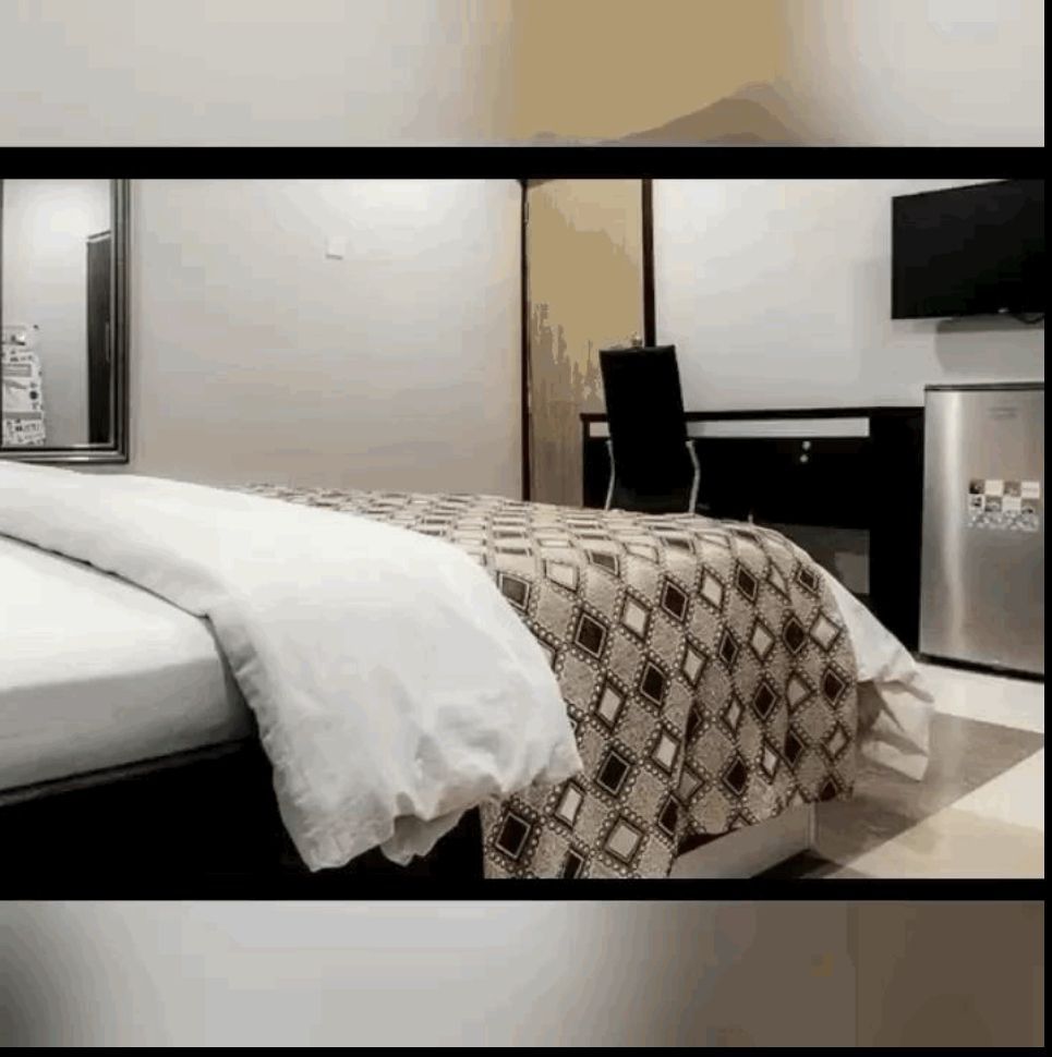 A hotel room with a bed , desk and television