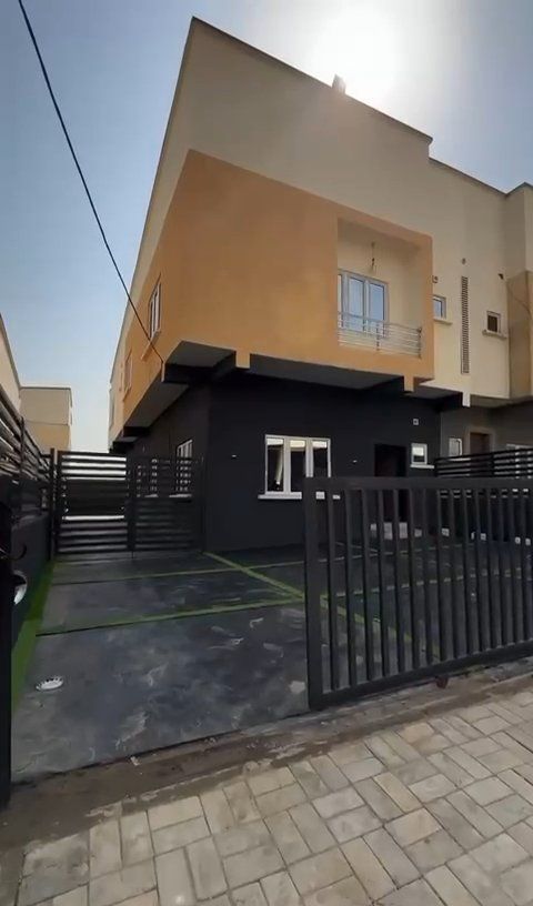 A house with a fence around it and a parking lot in front of it.