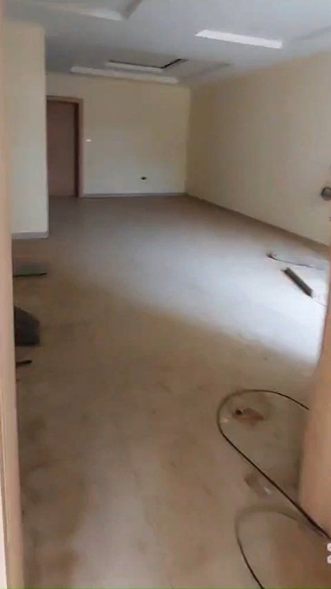 A large empty room with a glass table in the middle of it.