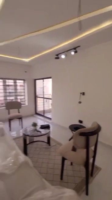 A living room with a table , chairs , and a window.