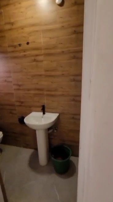 A bathroom with a sink , toilet , and bucket.