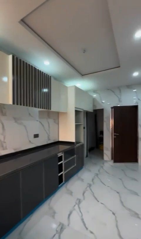 An empty kitchen with marble floors and cabinets