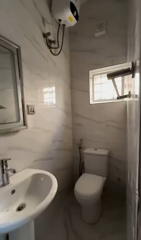 A bathroom with a toilet , sink and mirror.