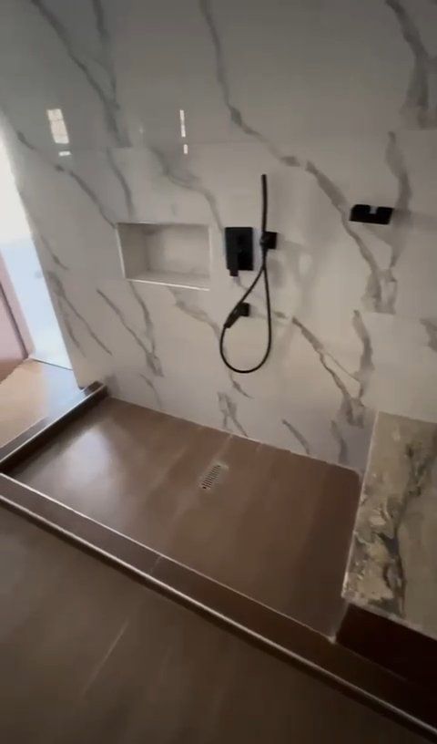 A bathroom with marble walls and a walk in shower.