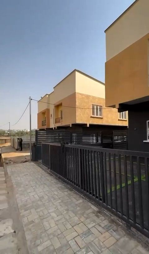 A brick walkway leading to a building with a black fence